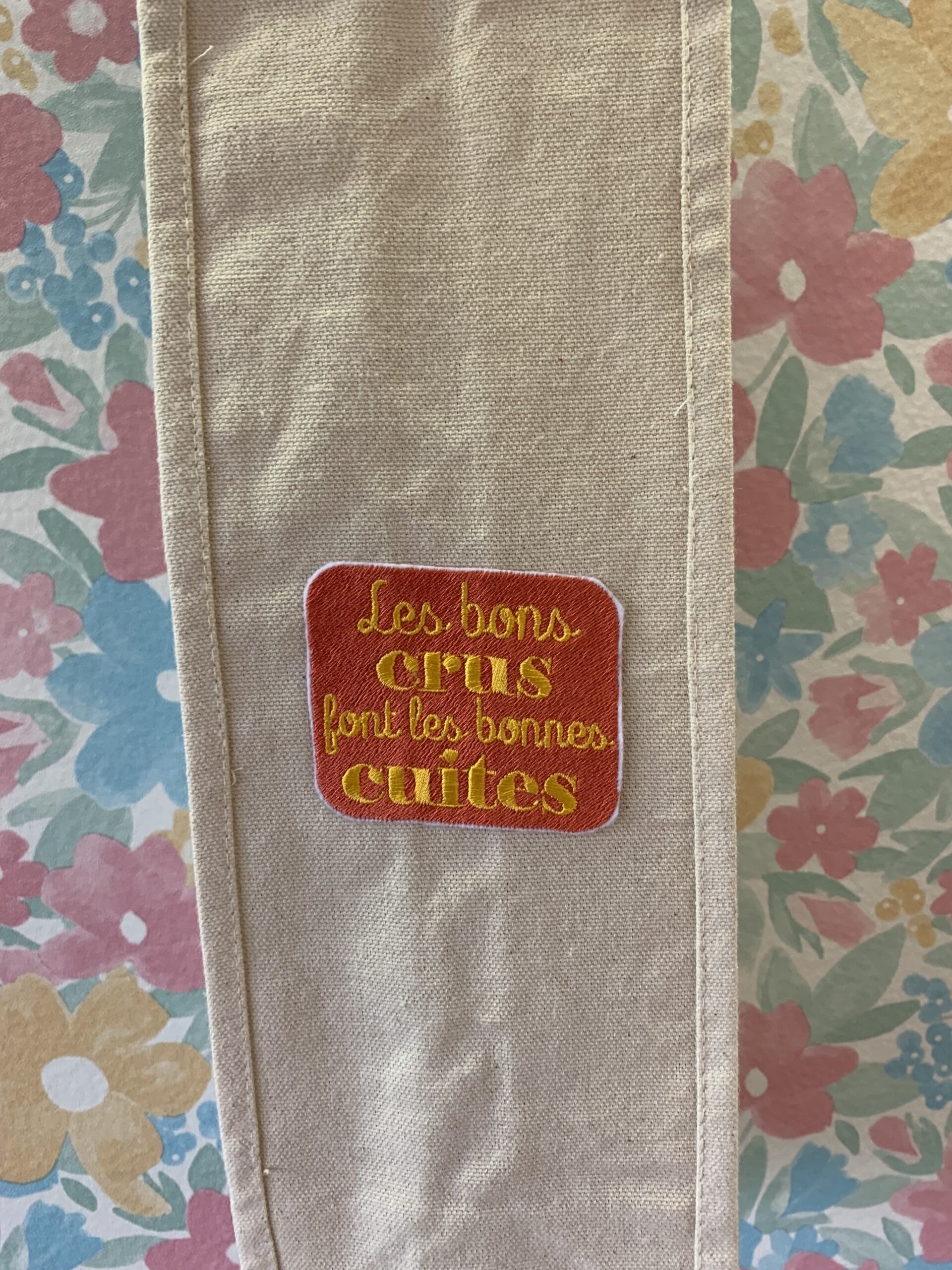 Détail de la broderie "les bons crus font les bonnes duites" d'un porte-bouteille