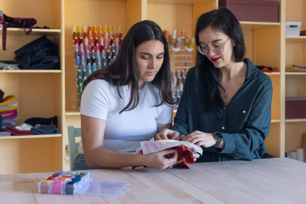 Julie, artisane brodeuse qui accompagne une élève lors d'un atelier d'initiation à la broderie main