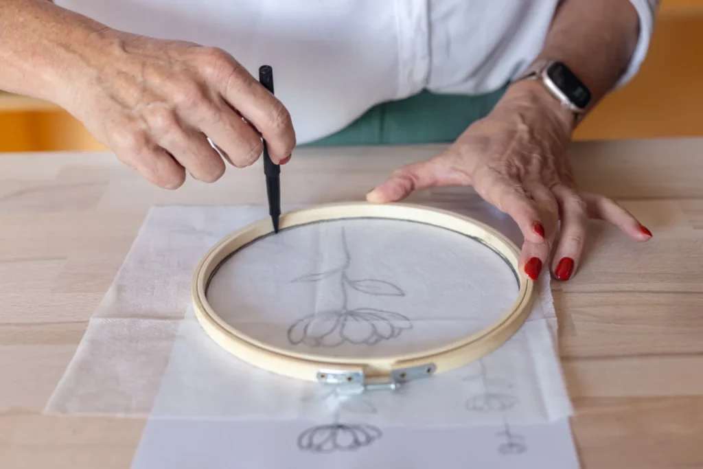 gros plan d'une main qui calque un motif lors d'un atelier d'initiation à la broderie main à Mérignac
