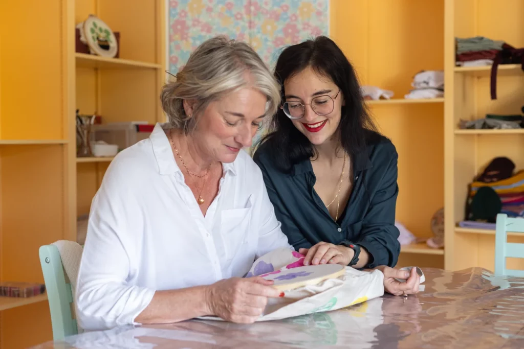 Julie artisane brodeuse qui accompagne une participante sur la façon de brodé lors d'un atelier d'initiation aquarelle et broderie main