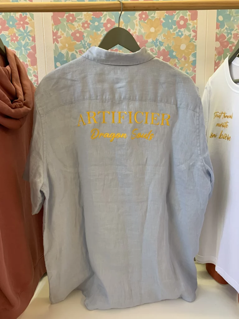 Broderie dans le dos d'une chemise professionnelle du nom de l'entreprise ainsi que sa fonction, en jaune