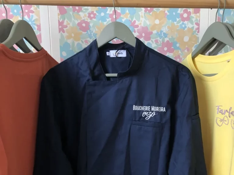 Veste de cuisine bleu brodé avec le nom d'une entreprise sur le coeur