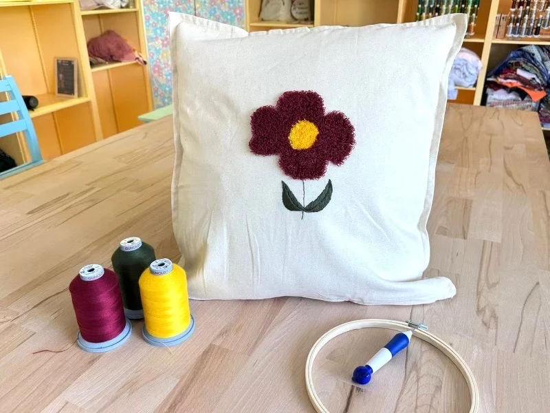 Housse de coussin réalisé lors d'un atelier d'initiation de broderie texturée, avec le motif d'une fleur en relief