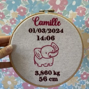 Décoration pour une naissance d'un bébé avec une broderie d'un motif éléphant, date de naissance, heure poids et taille du bébé.