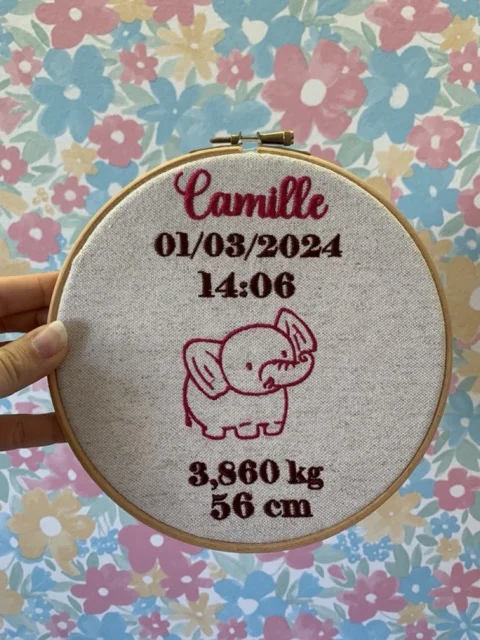 Décoration pour une naissance d'un bébé avec une broderie d'un motif éléphant, date de naissance, heure poids et taille du bébé.