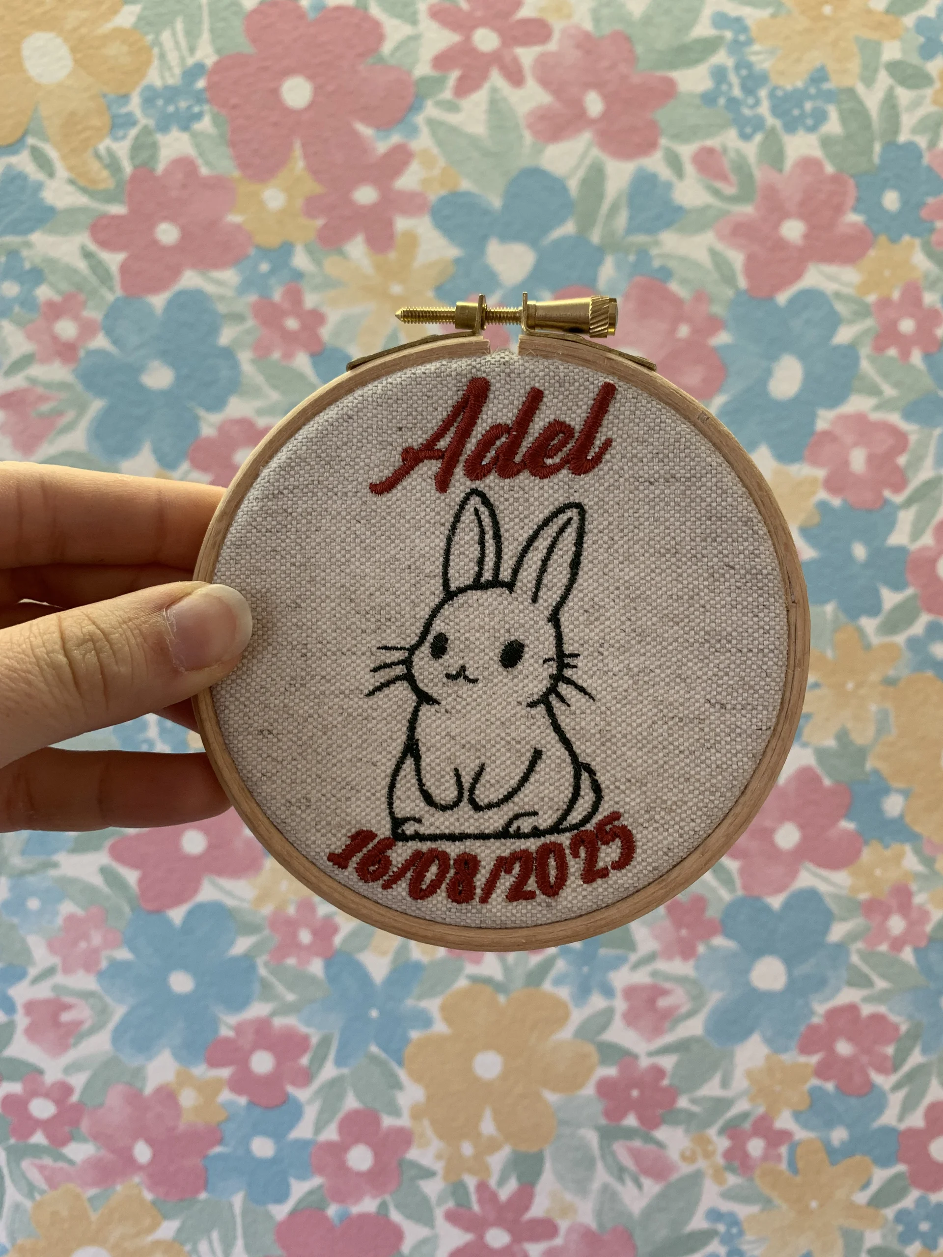 Broderie d'un lapin, du prénom du bébé ainsi que la date de naissance sur une décoration à offrir en cadeau de naissance