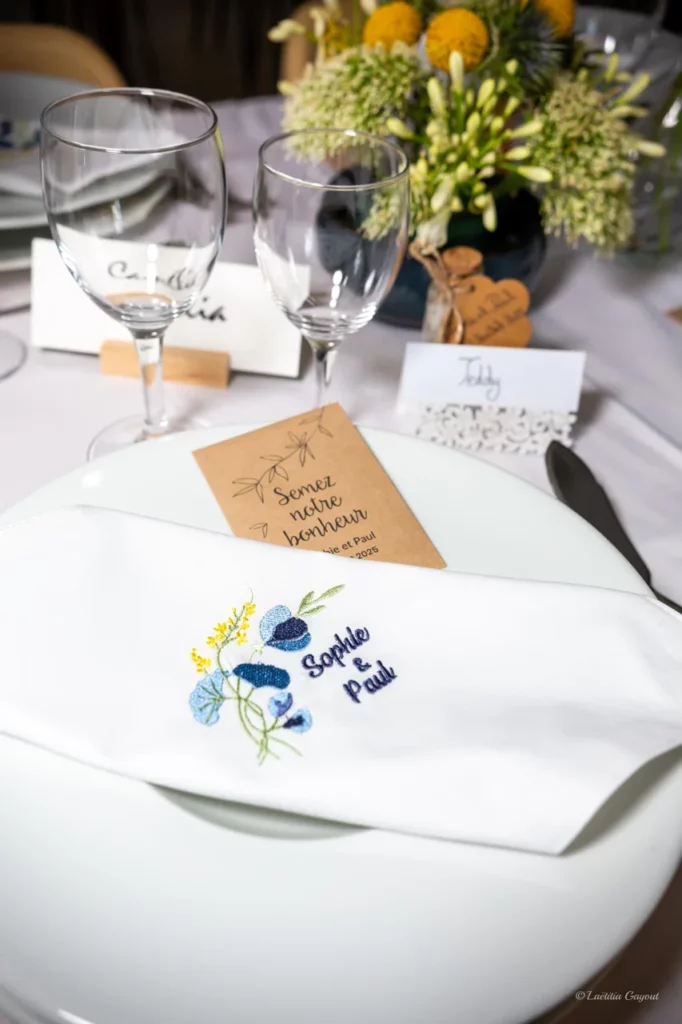 Serviette de table pour un mariage avec une broderie des prénoms des futurs mariés ainsi qu'une fleur