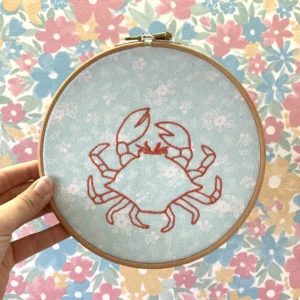 Broderie d'un crabe sur un tissu de seconde main bleu ciel avec des fleurs blanches, décoration intérieure en modèle unique