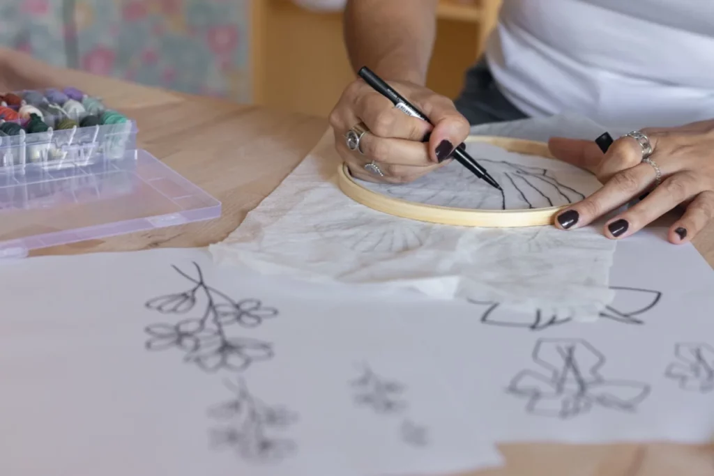 Gros plan d'un main en train de calquer un motif de broder lors d'un atelier d'initation à la broderie main