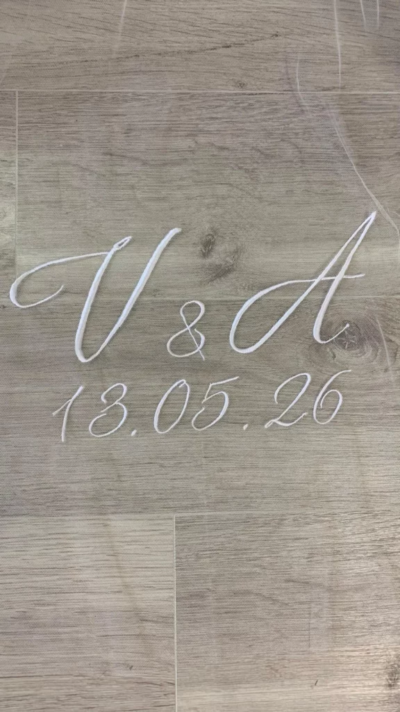 Gros plan d'initiales des futurs mariées ainsi que la date de mariage sur un voile en tulle