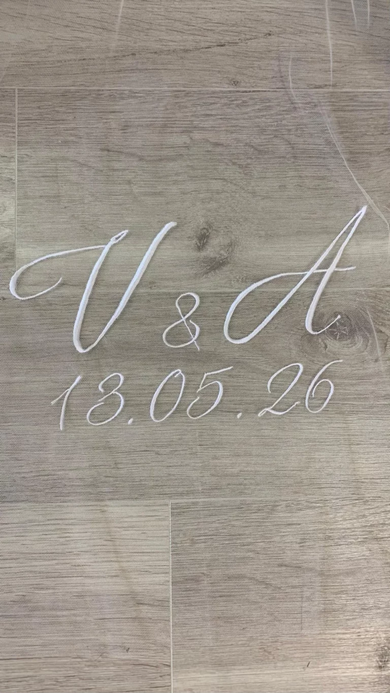Gros plan d'initiales des futurs mariées ainsi que la date de mariage sur un voile en tulle