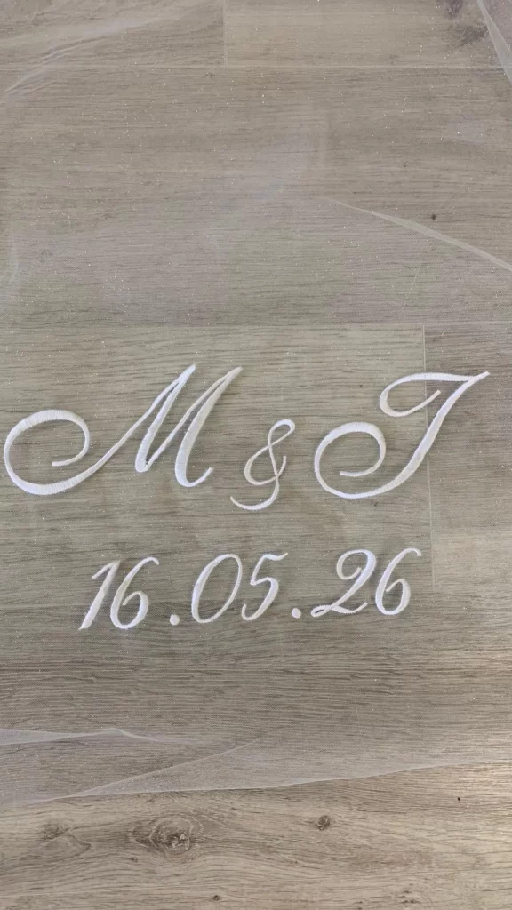 Gros plan d'initiales des futurs mariés ainsi que la date du mariage faite sur un voile de mariée