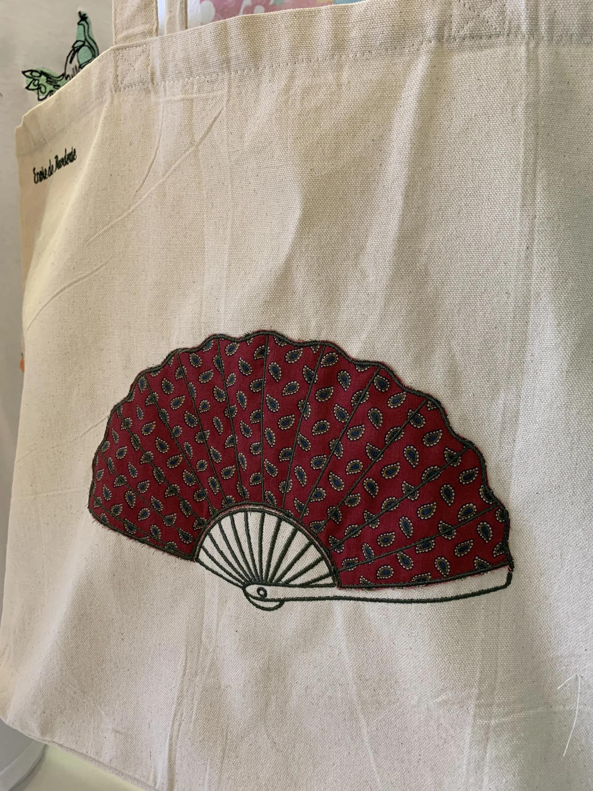 Gros plan du motif brodé éventail, avec les contours en broderie et l'intérieur un tissu de seconde main