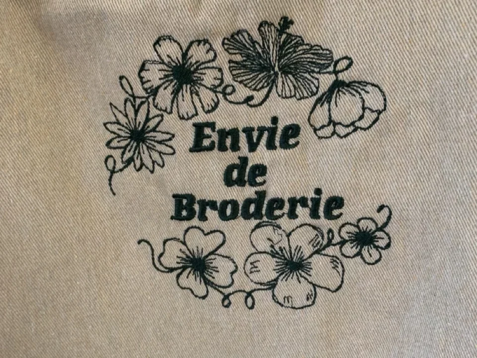 Gros plan du logo Envie de broderie, brodé sur l'avant d'un tablier