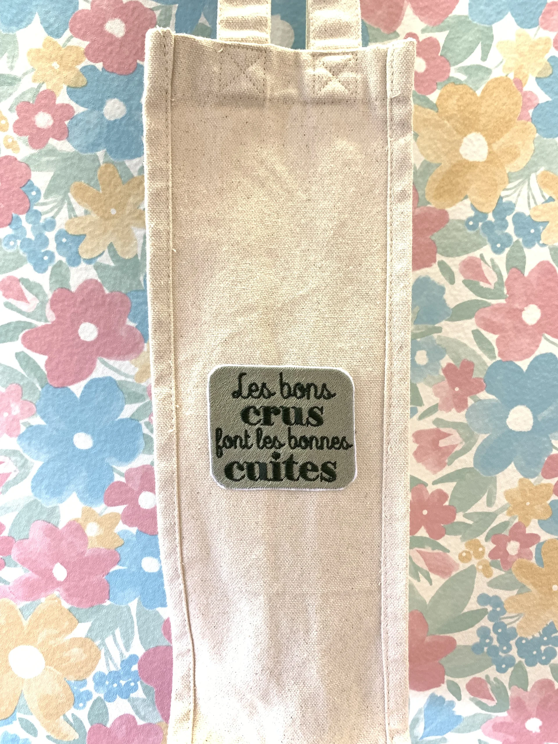 Porte bouteille avec un écusson brodé "Les bons crus font les bonnes cuites"