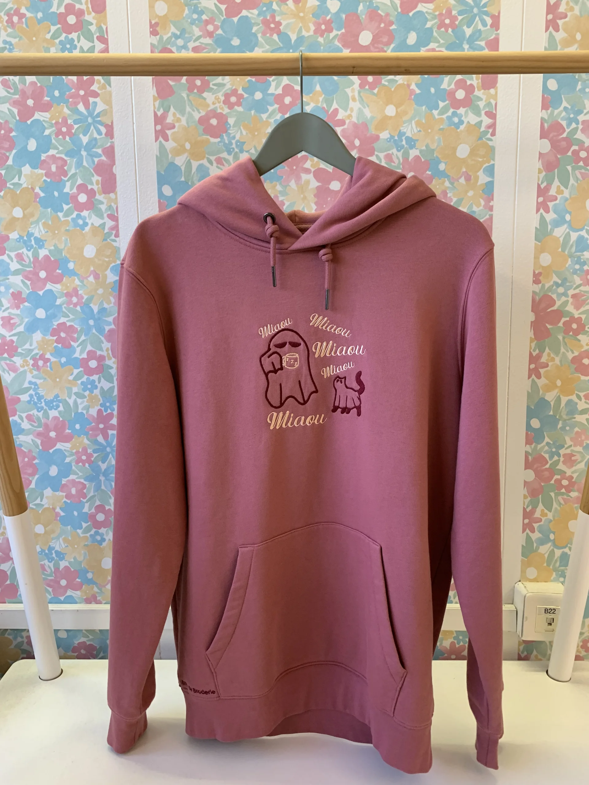 Vue de face du sweat rose brodé avec un fantôme buvant un café en compagnie de son fantôme chat qui n'arrête pas de miauler