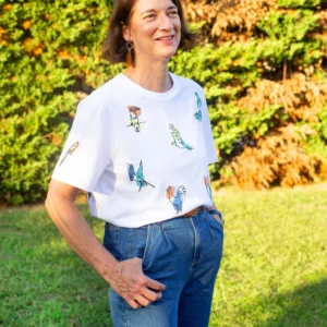 T-shirt blanc en coton biologique porté en extérieure, avec neuf broderies d'oiseaux sur le devant du textile
