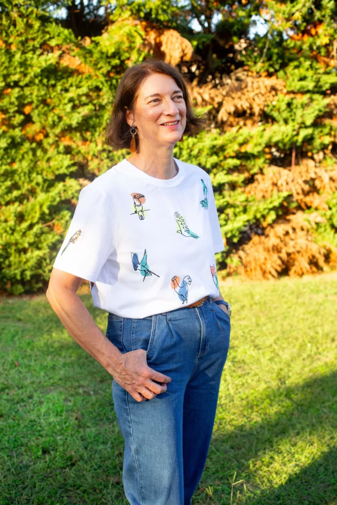 T-shirt blanc en coton biologique porté en extérieure, avec neuf broderies d'oiseaux sur le devant du textile