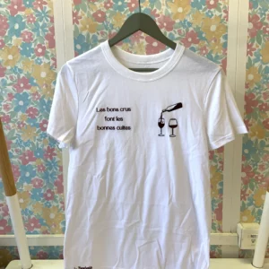 T-shirt blanc avec une broderie sur le coeur représentant une bouteille de vin et deux verres à vin et en contre-coeur brodé "les bons crus font les bonnes cuites"
