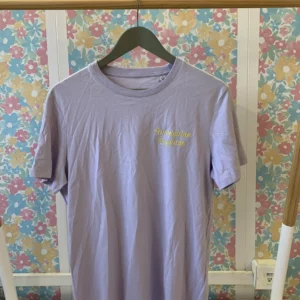 T-shirt de couleur parme avec une broderie coeur de couleur jaune, avec écrit en broderie le mot "parmigiano reggiano"