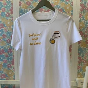 T-shirt blanc brodé sur le coeur d'un tonneau à bière avec la chope, et en contre-coeur une broderie de la phrase "tout travail mérite sa bière"