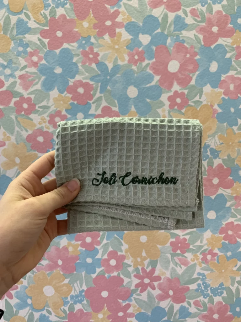 broderie du mot "joli cornichon" sur un torchon de cuisine de couleur vert