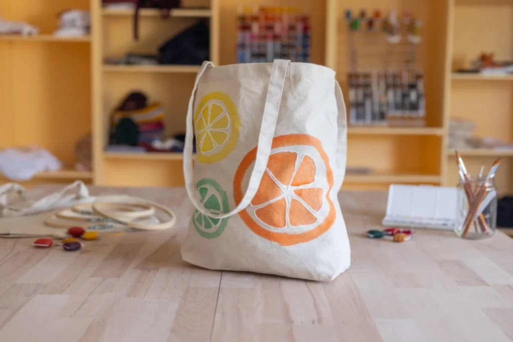 Tote bag peint à l'aquarelle et brodé à la main représentant des agrumes, réalisé lors d'un atelier d'initiation à l'aquarelle et broderie main